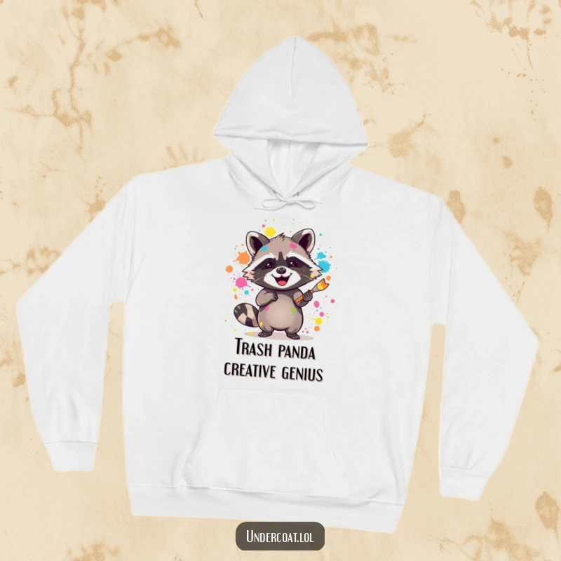 Funny raccoon hoodie with a joyful raccoon splattering vibrant paint with a brush, ideal for cozy creative sessions.